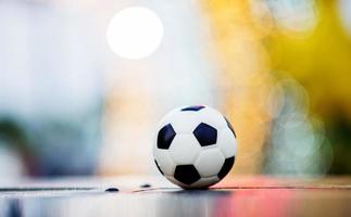 The soccer ball is placed on a wooden floor and has a blurred background with beautiful bokeh. photo