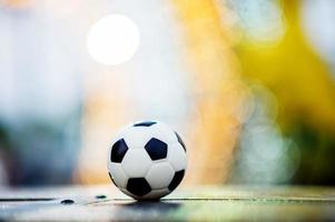 The soccer ball is placed on a wooden floor and has a blurred background with beautiful bokeh. photo