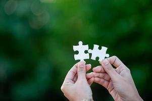 Hands and white jigsaw puzzles Close-up image and integration Business concept and unity photo