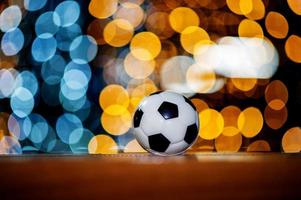 The white football ball is placed on a piece of wood and has a beautiful bokeh background. photo