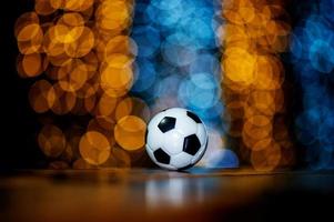 The white football ball is placed on a piece of wood and has a beautiful bokeh background. photo