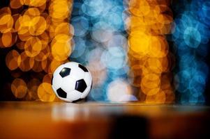 The white football ball is placed on a piece of wood and has a beautiful bokeh background. photo