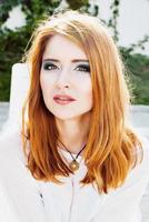 Portrait of young beautiful red-haired woman in sunny day photo