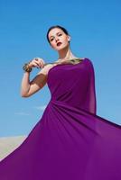 Amazing beautiful brunette woman with the Peacock feather in purple fabric in the desert. Oriental, indian, fashion, style concept photo