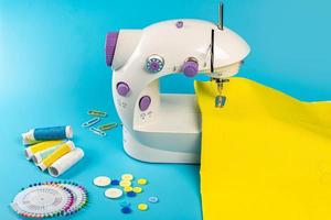 máquina de coser con tela amarilla sobre fondo azul foto