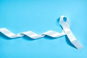 cinta blanca como símbolo de violencia femenina o cáncer de pulmón en el fondo azul foto