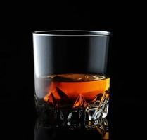 whisky escocés en un vaso elegante sobre un fondo negro con reflejos. foto