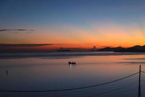 Scenic view from silhouette of fishing boat in calm ocean during sunrise photo