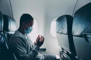 Muslim passenger in medical mask praying inside an airplane photo