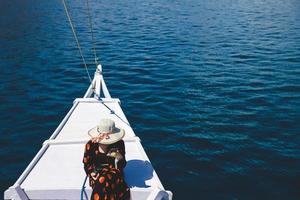 Women tourist in summer hat sitting on boat deck enjoying trip at Labuan Bajo