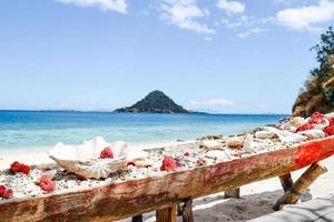 Coral reefs collected in long wooden containers on the beach with seascape and mountain at Labuan Bajo photo
