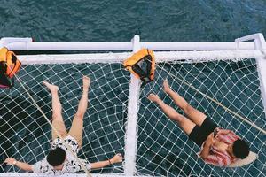 Two male is relaxing and sun tanning on catamaran net while using a smart phone photo