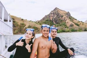 Happy asian tourists in diving goggles take a picture together on the boat at Labuan Bajo photo