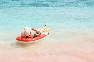 Woman in summer hat lying on inflatable water mattress in pink sandy beach at Labuan Bajo photo