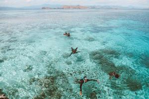 turistas asiáticos nadando y buceando en el agua de mar transparente foto