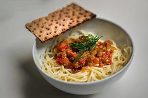 Pasta with tomato sauce in round bowl with cracker photo