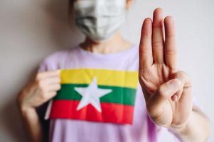 Young protest woman showing three-finger salute to against the Myanmar military coup. This gesture becoming a symbol of resistance and solidarity for democracy movements across south-east Asia. photo