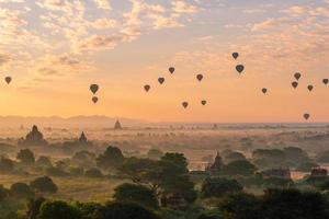 grupo de globos aerostáticos que vuelan sobre la antigua pagoda en la llanura de bagan al amanecer. bagan ahora es el sitio del patrimonio mundial de la unesco y el primer reino de myanmar. foto