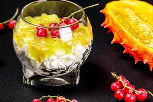 Cottage cheese with fresh kiwano and red currant berries on a black background photo