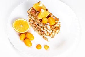 Slice of cake with condensed milk, nuts and citrus, top view photo