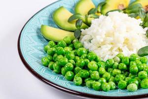 Rice with fresh avocado, green peas and sunflower microgreens photo