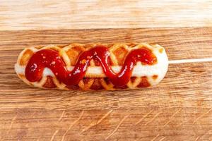 Corn dog with ketchup on wooden background photo