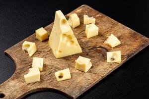 Slices of fresh Maasdam cheese on an old wooden kitchen board
