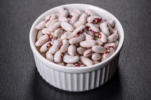 White dry raw beans on a dark concrete background photo
