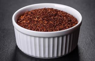 Rooibos tea on a black background. Flat lay, copy space photo