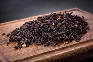 Black Ceylon tea - Top view of black tea background with green leaves photo