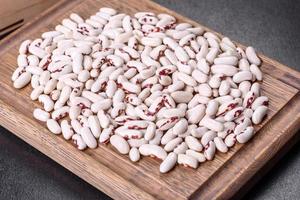 White dry raw beans on a dark concrete background