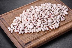 White dry raw beans on a dark concrete background