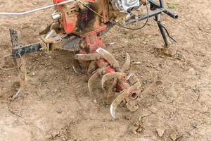 Small farm tractor plows the ground, the work of a walk-behind tractor photo