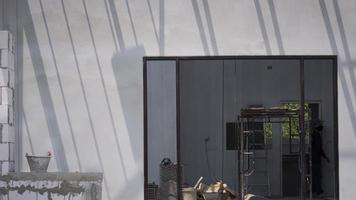 Sunlight and shadow on surface of concrete wall with construction material and equipment in door frame inside of house construction site photo