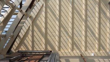 luz solar y sombra en la superficie de la estructura de vigas de techo de madera blanca con material de construcción en la parte superior del sitio de construcción de la casa foto