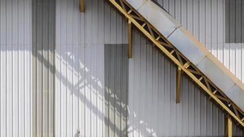 Part of the old yellow conveyor line on metal sheet wall of warehouse building photo