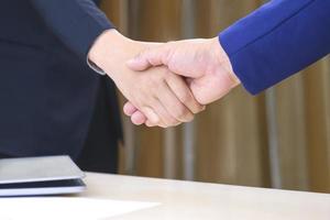 Close up 2 business people shaking hands during meeting in office room, partnership and cooperation concept photo