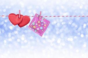 2 fabric red hearts and pink condom hanging on rope string with blurred silver glitter sparkle background, safe sex with birth control and family planning concept photo