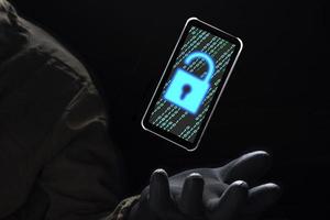 Close up illuminate unlock icon with green binary code on screen of smartphone floating above of hacker's hand in black glove on dark background, hacking and internet cyber crime concept photo