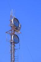 Communication telecom tower with radar and antennas against blue clear sky in vertical frame photo