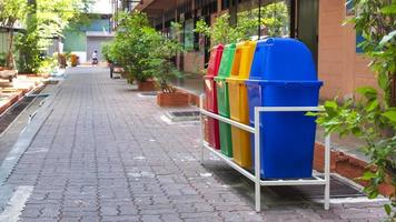 Perspective and side view of multicolored garbage bins on brick pavement in the school photo