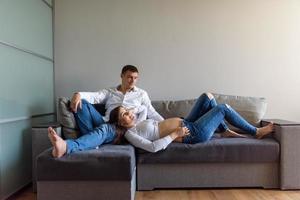 A man and a pregnant woman are sitting hugging on the couch. photo