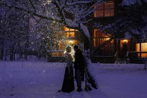 Beautiful bride and groom with a white dog are standing on the background of a snowy forest. photo