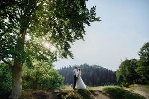 Photoshoot of a couple in love in the mountains. The girl is dressed like a bride in a wedding dress. photo
