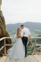 Photoshoot of a couple in love in the mountains. The girl is dressed like a bride in a wedding dress. photo