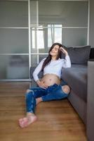 A man and a pregnant woman are sitting hugging on the couch. photo