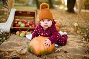 Little girl leans on a pumpkin. photo