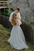 Photoshoot of a couple in love in the mountains. The girl is dressed like a bride in a wedding dress. photo