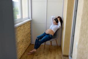 A man and a pregnant woman are sitting hugging on the couch. photo