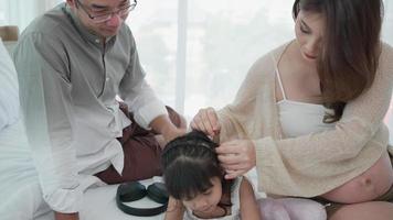 Pregnant Woman Tie Hair of Daughter and Sitting Together With Husband at home